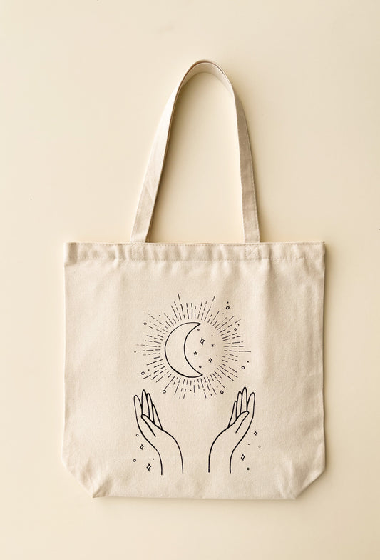 Canvas tote bag with hands holding moon and sparkles
