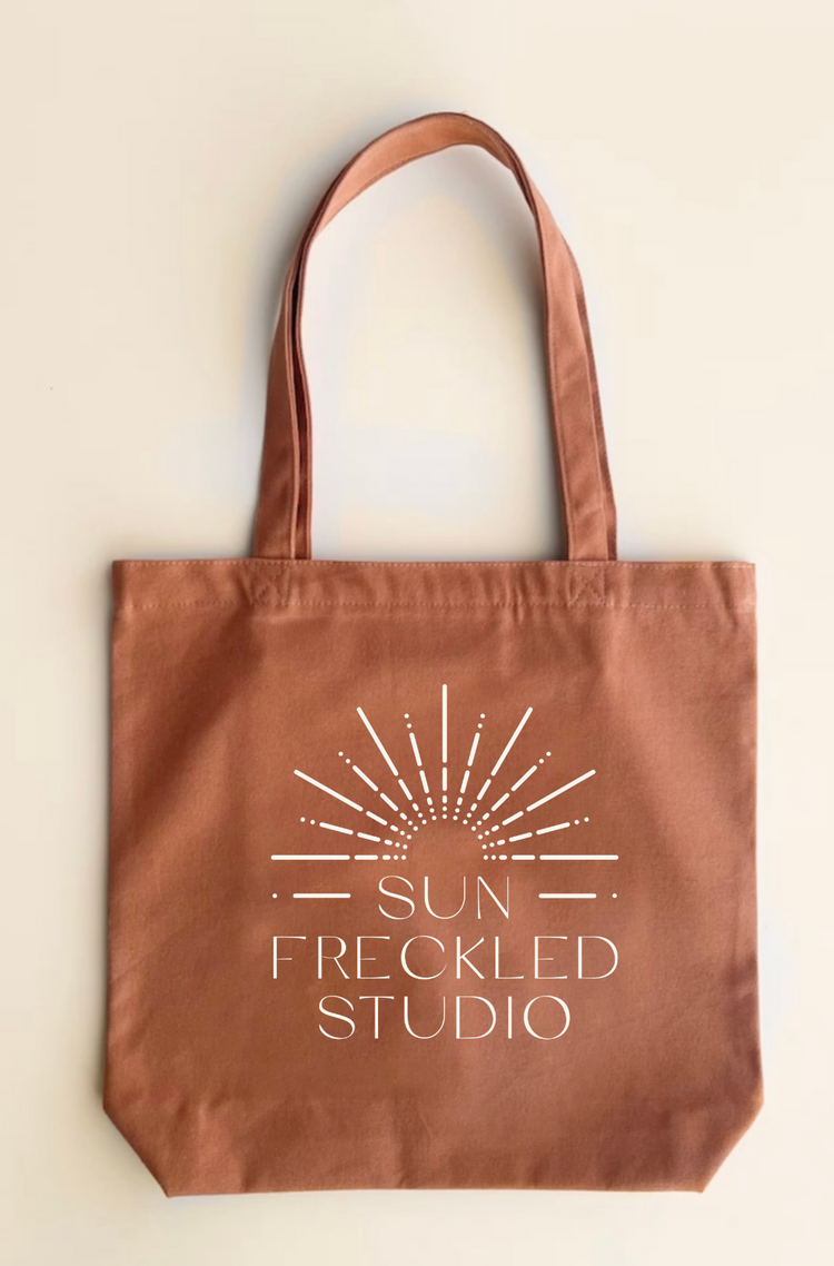 Brown canvas tote bag with sun freckled studio logo